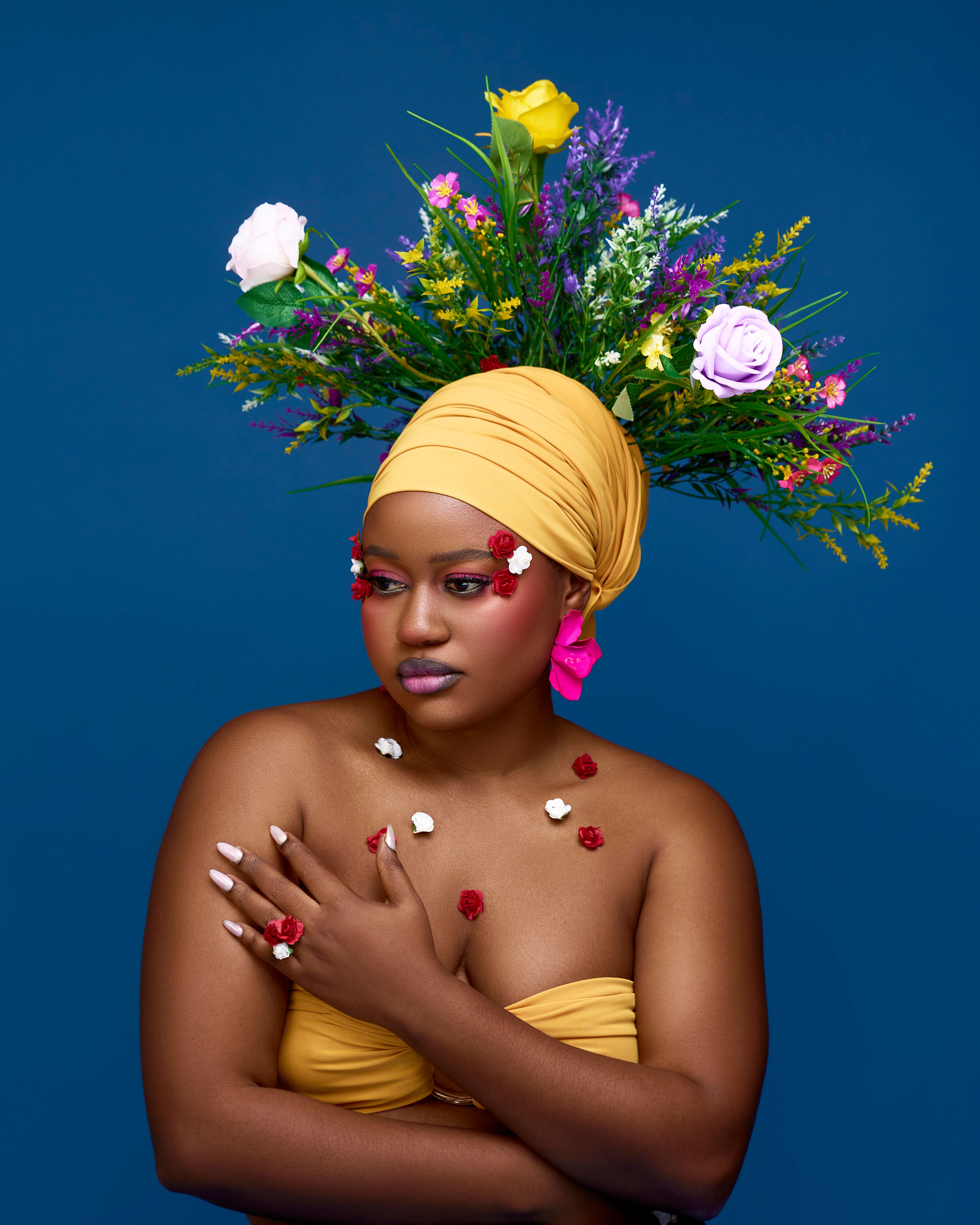 Striking portrait of a woman with a unique floral headpiece against a blue background.