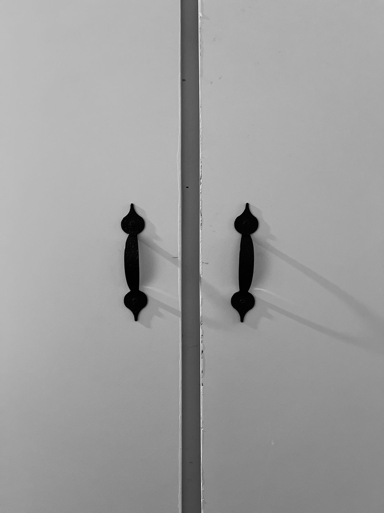 Black bar handles mounted vertically on white cabinet doors