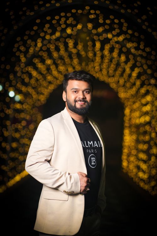Free Fashionable man in white blazer poses against a backdrop of golden bokeh lights. Stock Photo