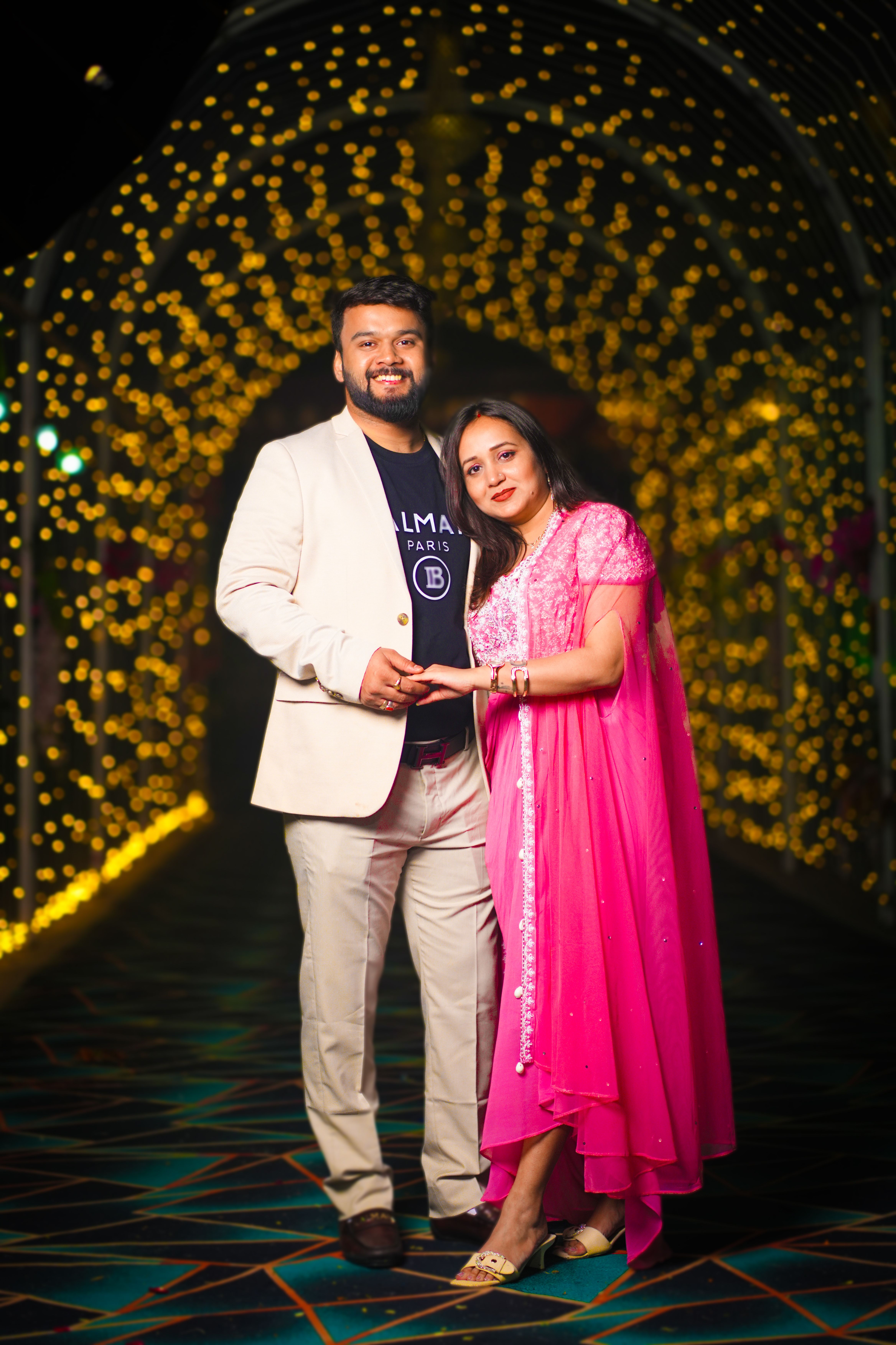 Smiling couple under a canopy of twinkling lights, creating a romantic and festive atmosphere.