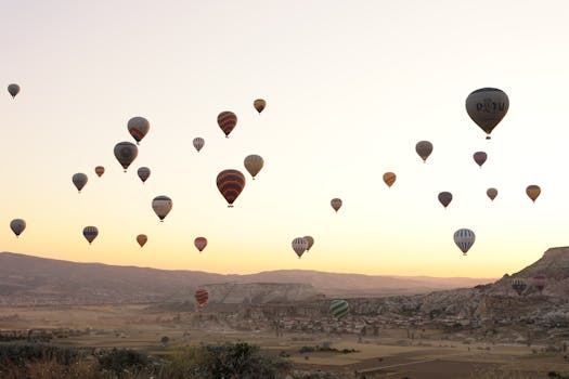 A stunning view of hot air balloons floating over Göreme, Türkiye at sunrise.