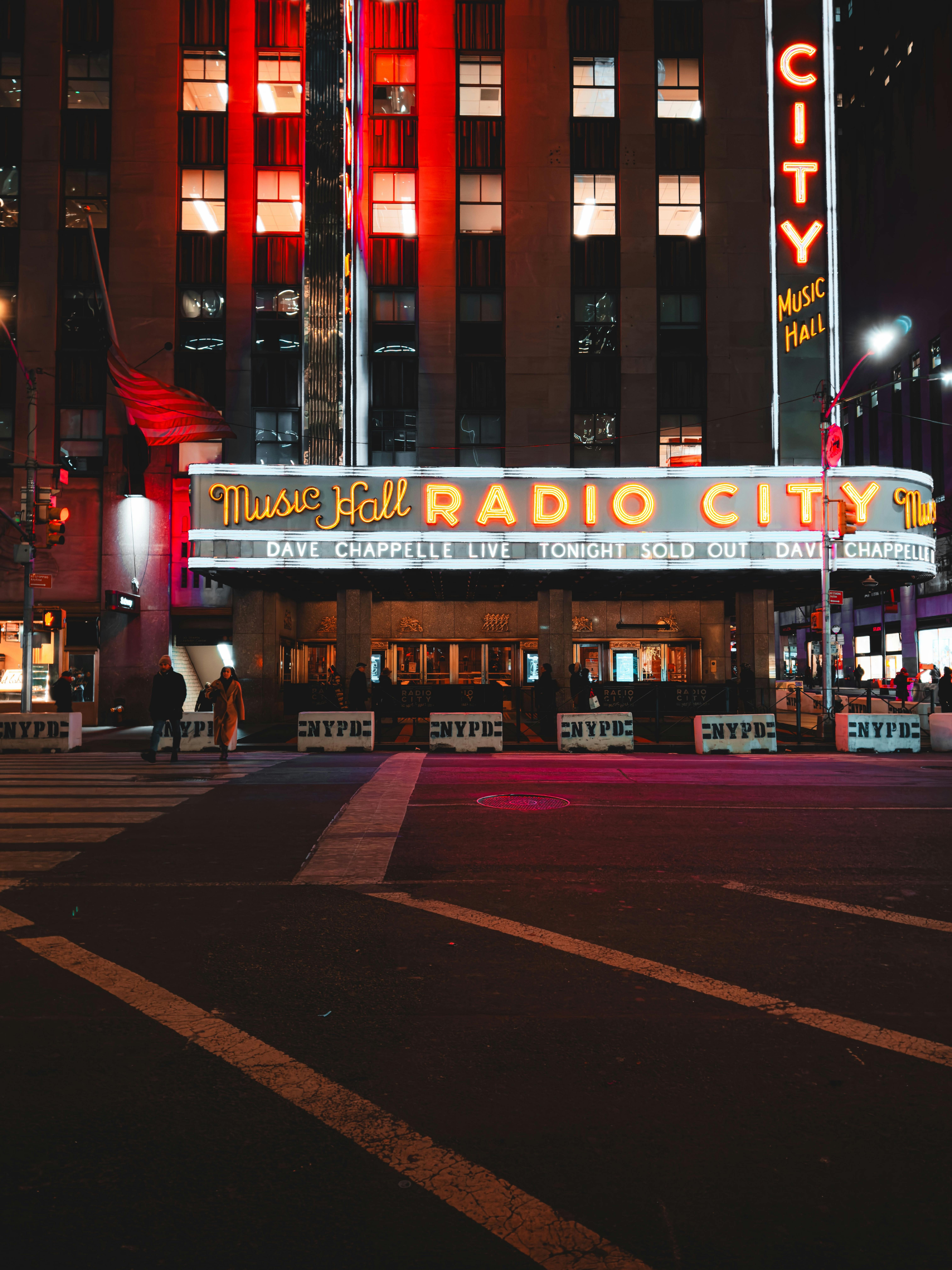 Free Stunning night view of Radio City Music Hall in New York City, vibrant lights illuminating the street. Stock Photo