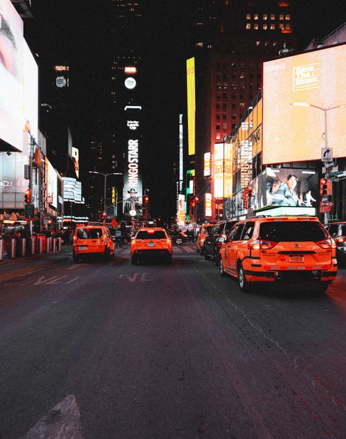 Free Nighttime scene in Times Square featuring bright billboards and iconic New York taxis. Stock Photo