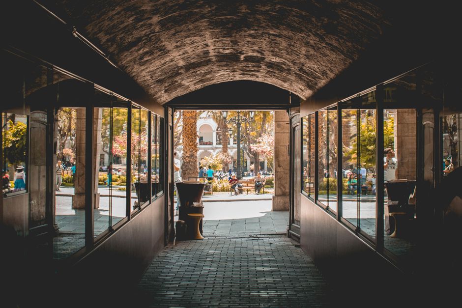 Hermosa vista de la ciudad de Arequipa a través de un arco con reflejos, mostrando la vida urbana.