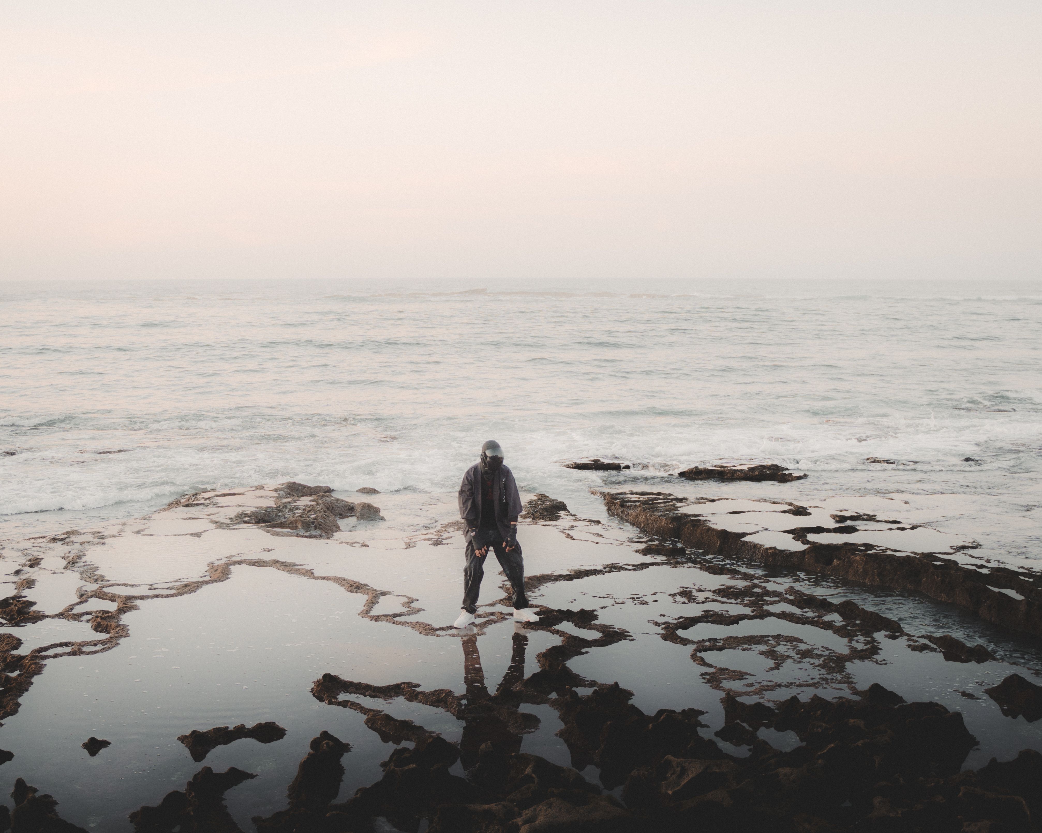 Solitary Figure on Coastal Rocky Shore at Twilight · Free Stock Photo