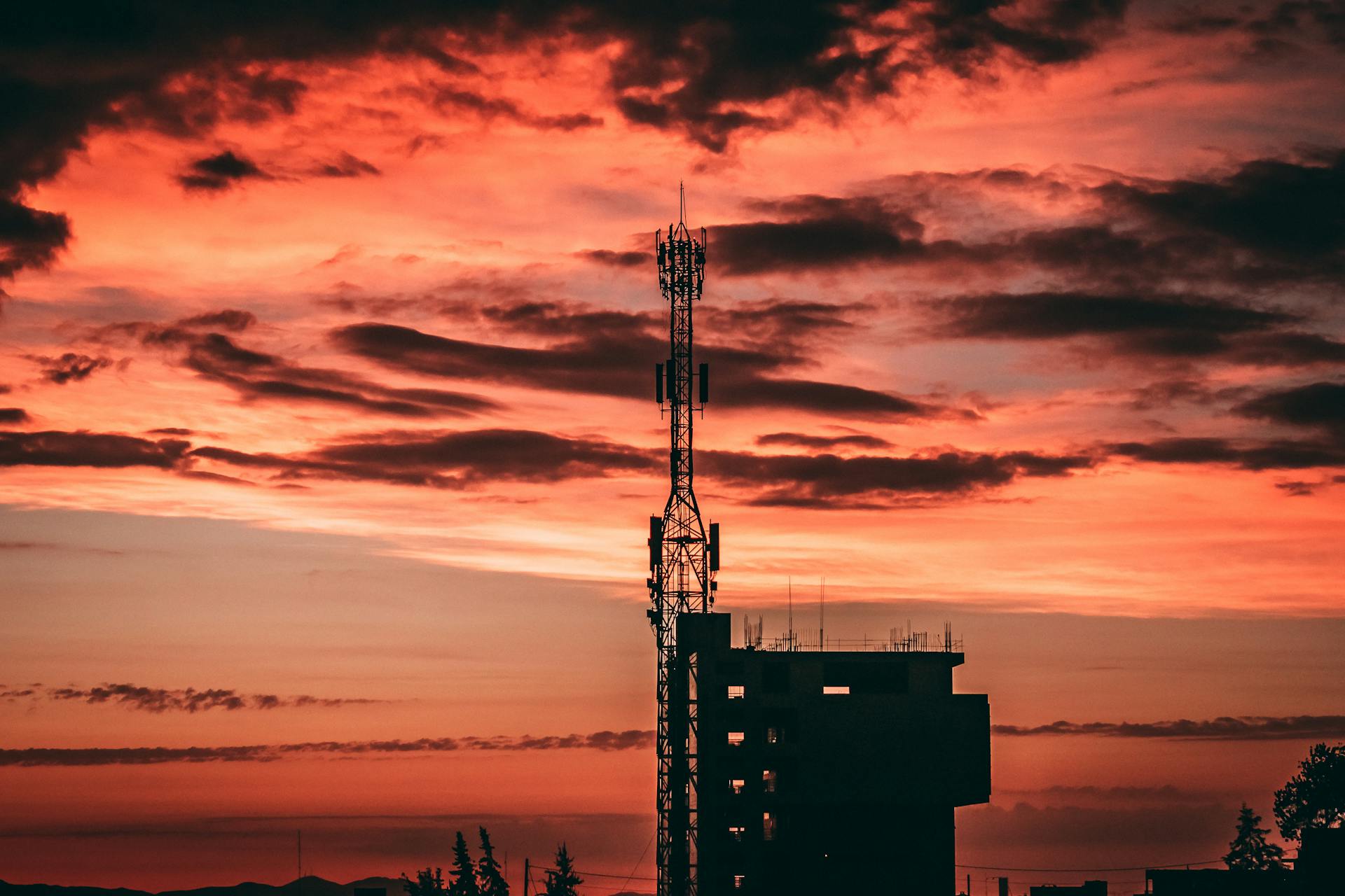 Beautiful sunset in Arequipa, Peru with silhouette of a communication antenna against vibrant orange skies.