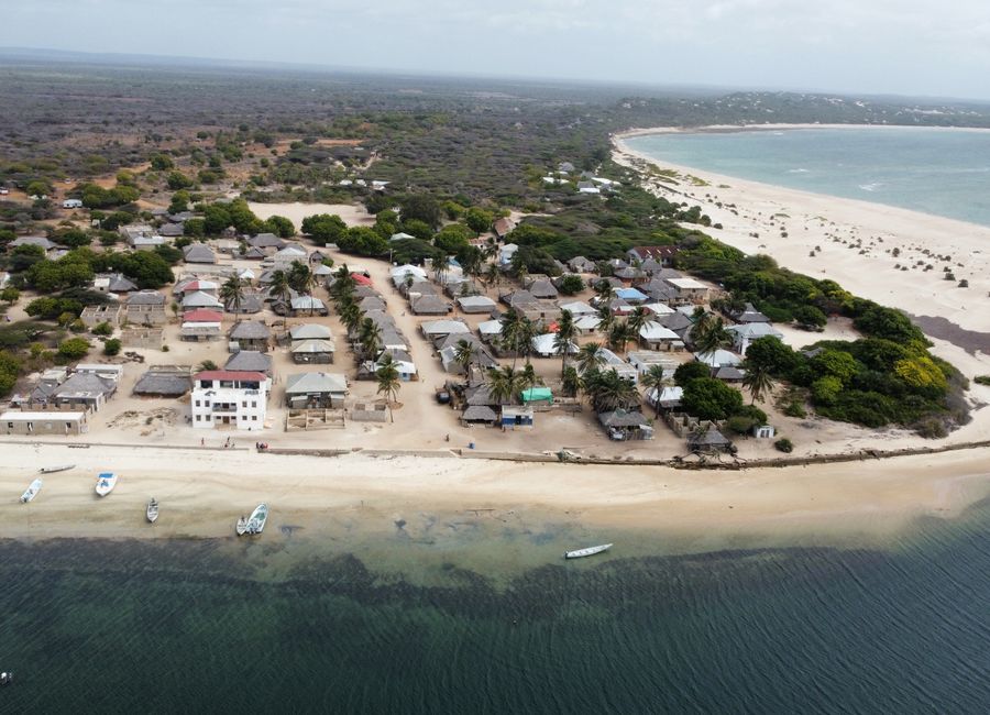 A stunning aerial shot of a coastal village in Lamu County, Kenya, featuring sandy beaches and clear ocean waters.