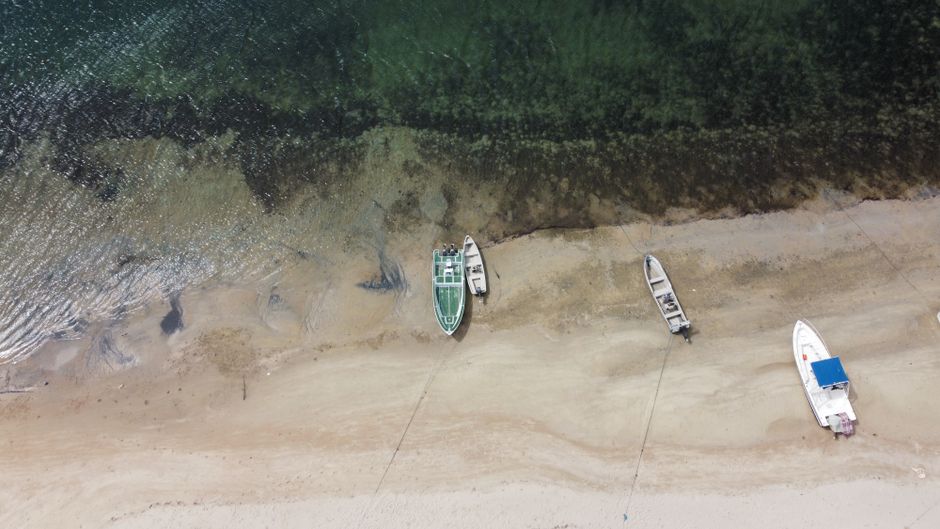Drone shot of boats on sandy beach in Lamu County, Kenya.