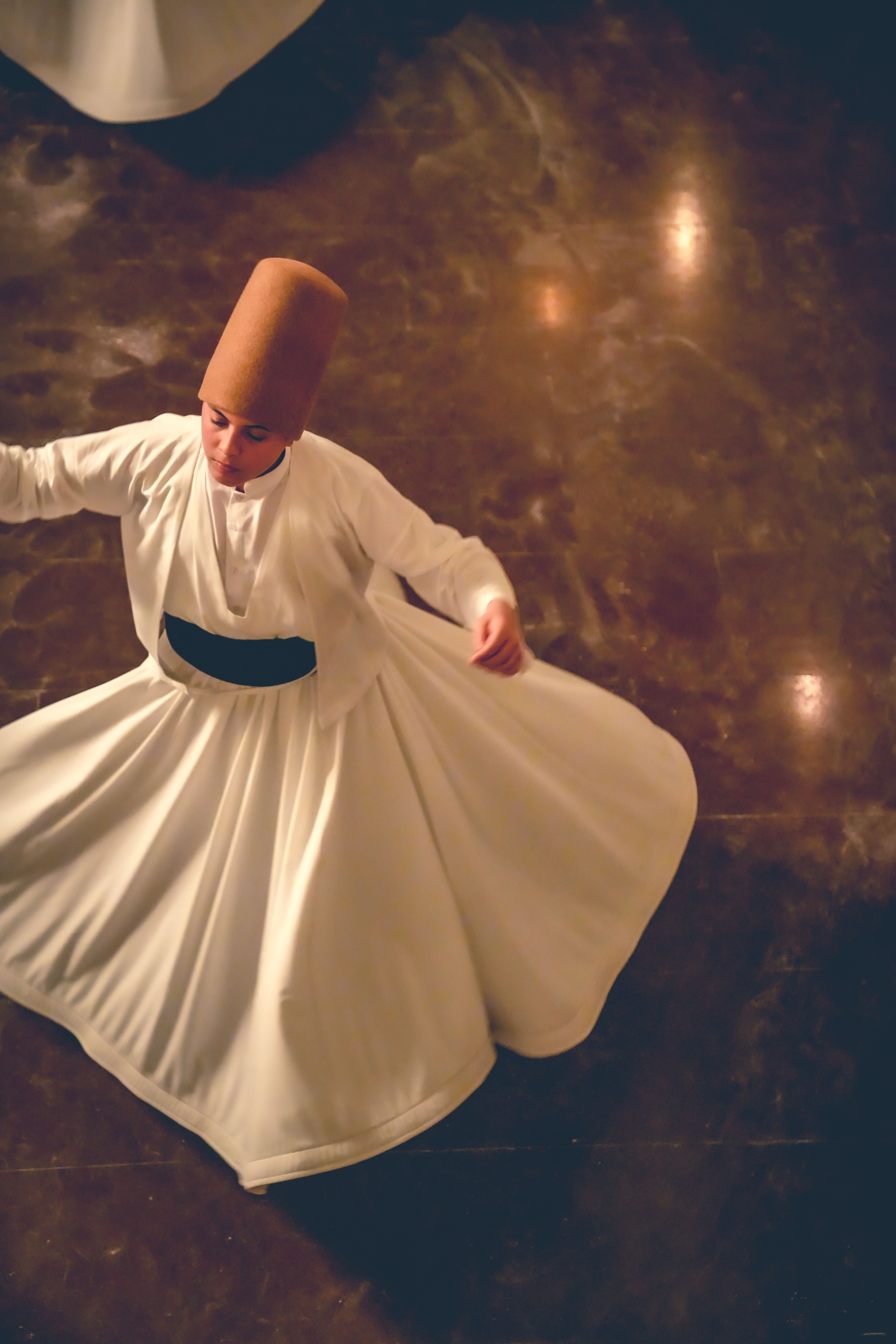 A dervish performs the traditional Sufi whirling dance in a dimly lit setting in Bursa, Türkiye.