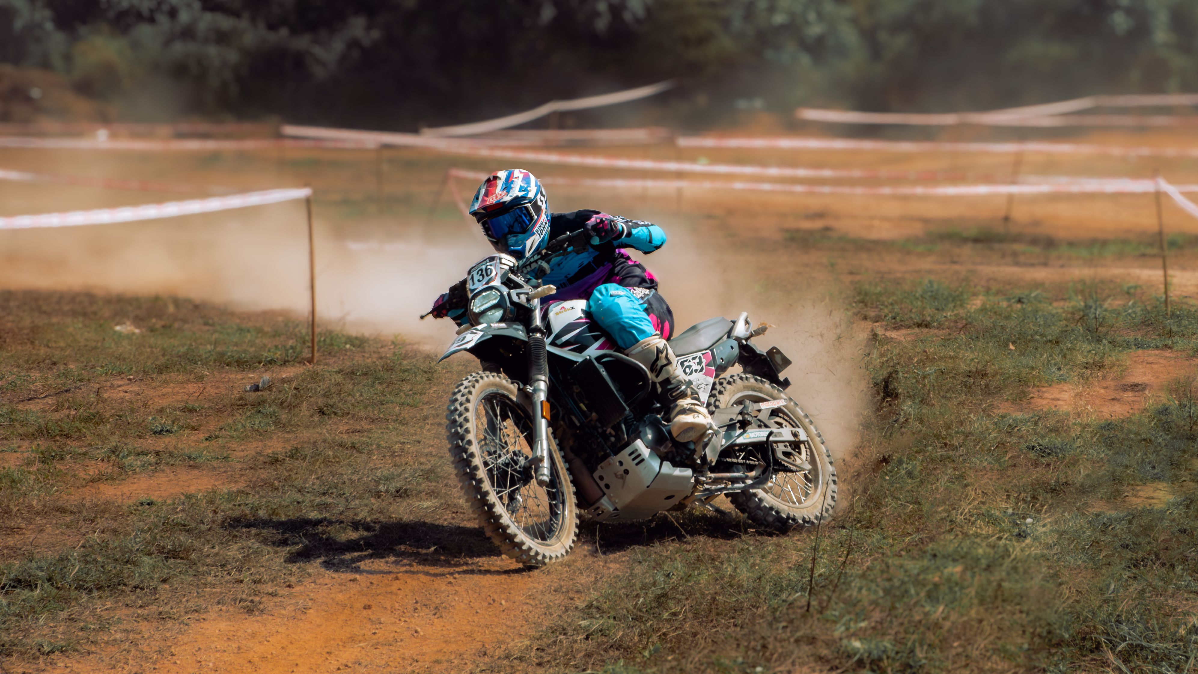 Motocross rider leaning into a sharp turn on a dusty dirt track.