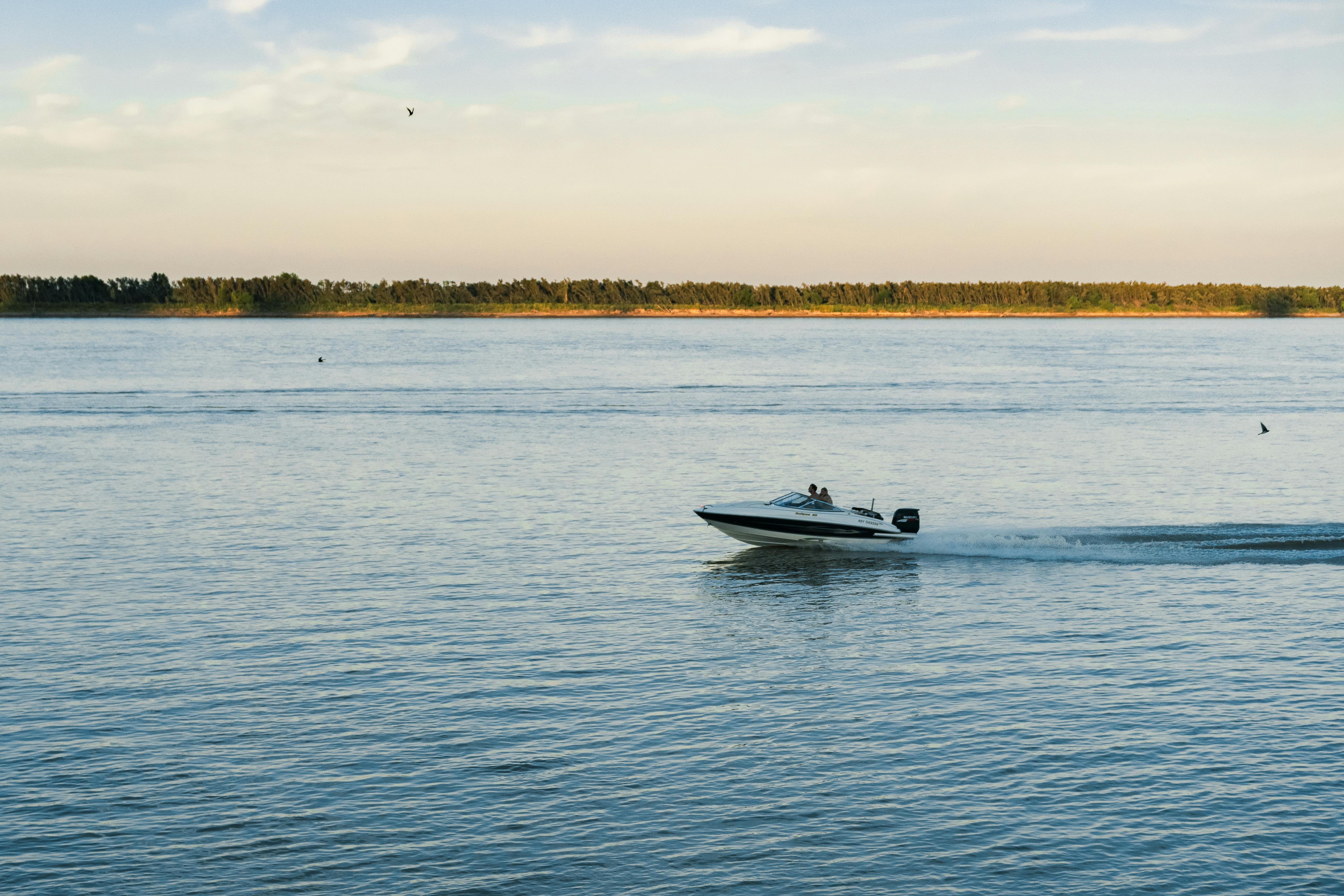 A speedboat cruises on the Parana River during a serene sunset in Rosario, Argentina.
