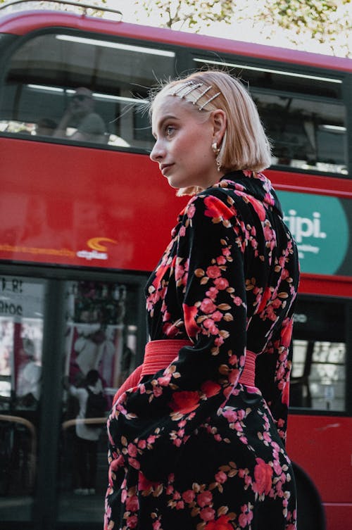 Mulher Usando Vestido Floral Preto E Vermelho De Mangas Compridas Em Pé Perto Do ônibus Vermelho De Dois Andares