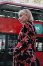 在著名的伦敦双层公共汽车附近的花卉服装的时髦的年轻女子