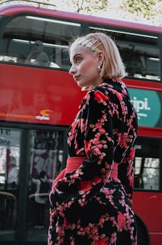 一位时尚的年轻女子身着花卉服装，站在著名的伦敦双层巴士旁