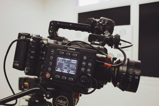 Close-up of a professional video camera setup on a tripod, ready for filming in a studio environment.