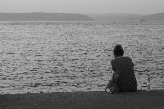 A lone person sits on a pier, gazing at the peaceful waters, exuding solitude and contemplation.