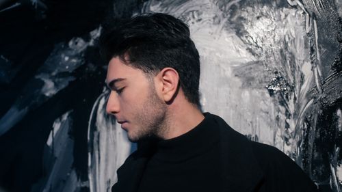 Free Side profile of a young man in black against a textured black and white background. Stock Photo