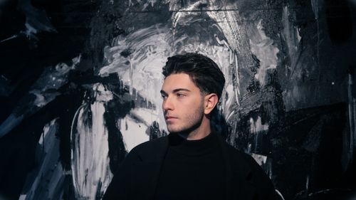 Free Stylish portrait of a man with dark hair in front of an abstract black and white background. Stock Photo