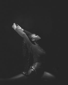 Artistic black and white image of a person gracefully posing in a dance stretch.