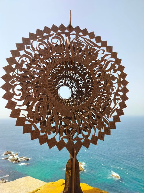 Free Intricate metal sculpture with ocean backdrop, showcasing artistic design and coastal beauty. Stock Photo
