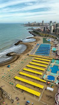 Aerial view of a vibrant beach cityscape with colorful umbrellas and modern architecture.