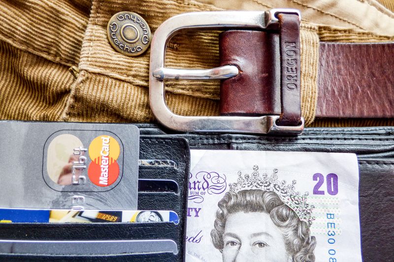 A detailed image of a wallet containing credit cards, a leather belt, and currency, emphasizing personal finance.