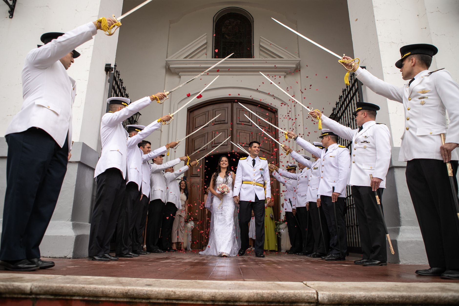 Bride and groom exit through military sword archway, celebrating their wedding in Córdoba, Argentina.