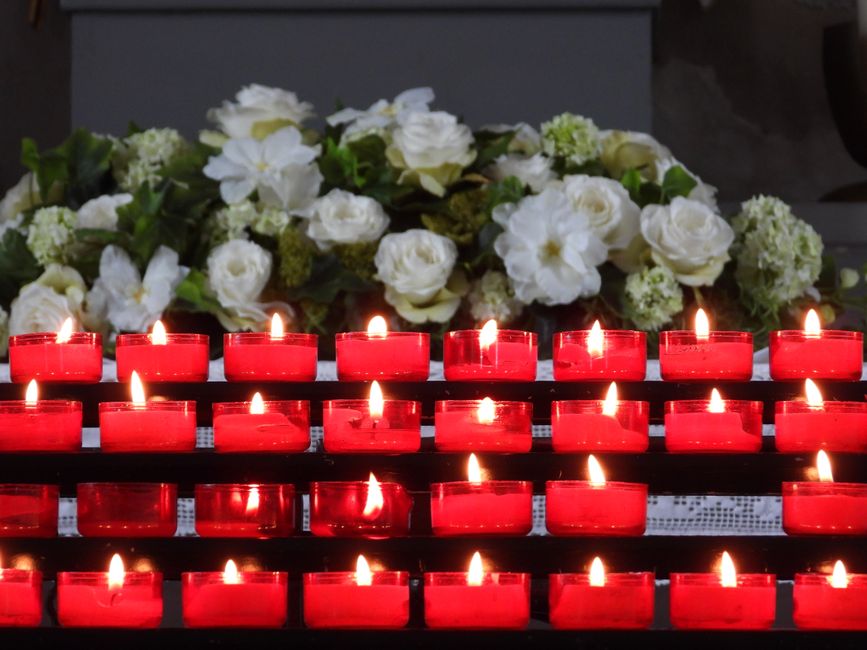 Close-up of candles and flowers being offered during a traditional <span class="notranslate"><em>Romaria</em></span>.