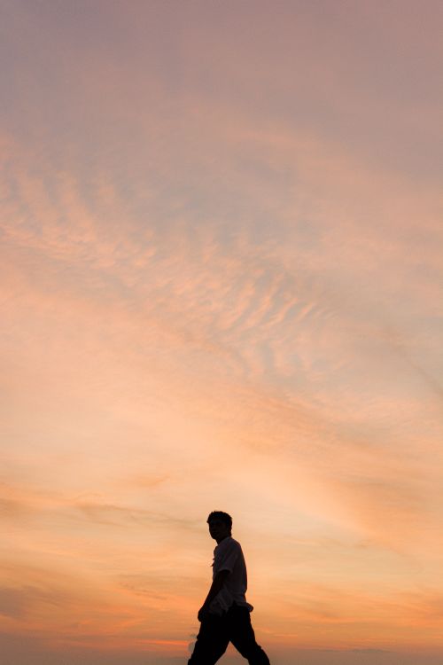Free Silhouette of a person walking against a vibrant sunset sky Stock Photo