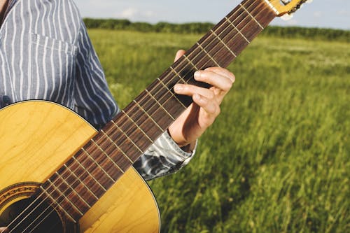 Person Playing Guitar in Grass Field