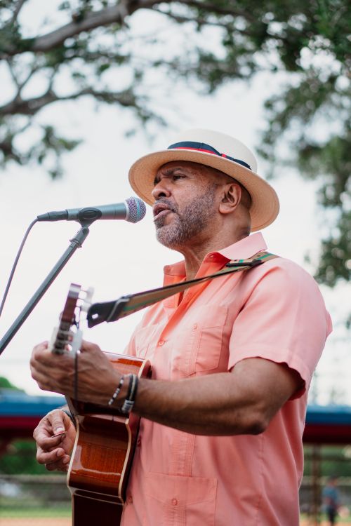 Free A man sings and plays guitar in a Miami park, expressing emotions outdoors. Stock Photo