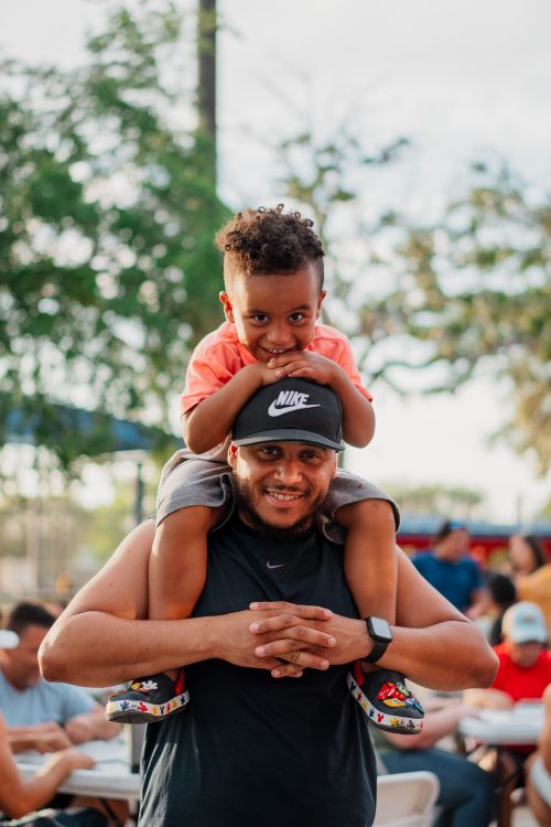 Free Happy father with son on shoulders enjoying a sunny day at a Miami park. Stock Photo