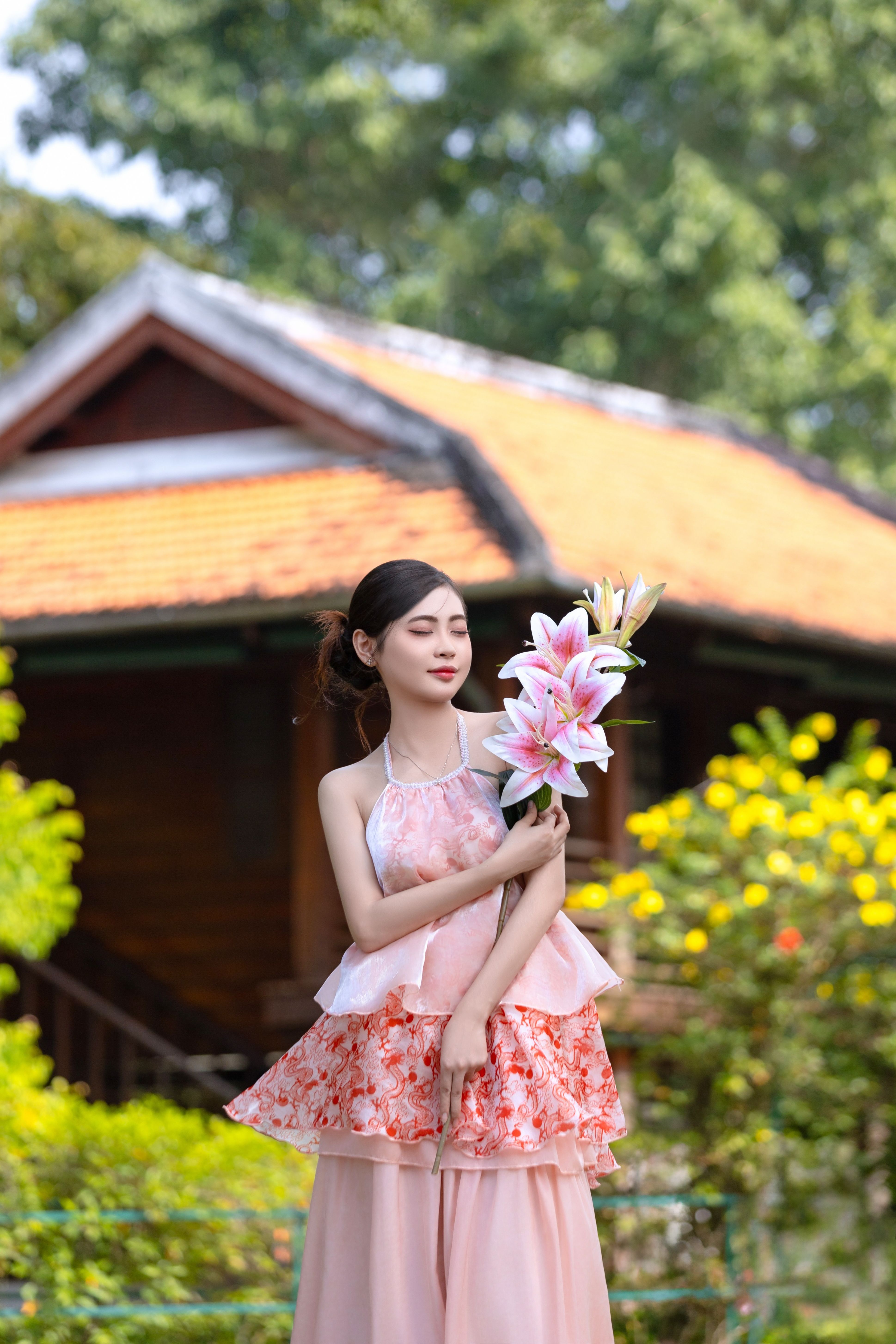 Young Woman in Floral Dress Holding Lilies Outdoors · Free Stock Photo