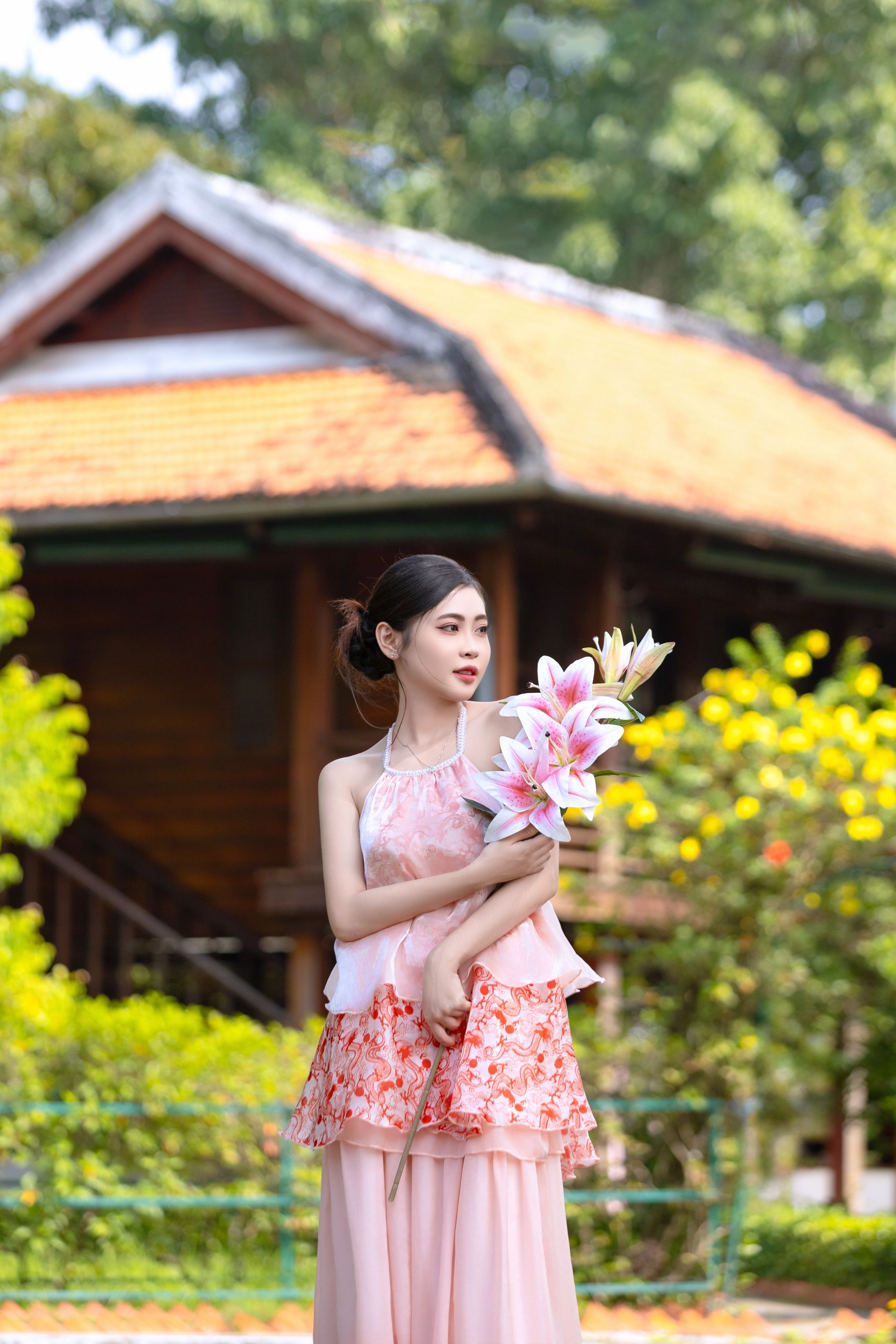 Young Woman in Floral Dress Holding Lilies in Garden · Free Stock Photo