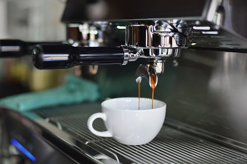 咖啡機上的白色陶瓷杯裝滿棕色液體