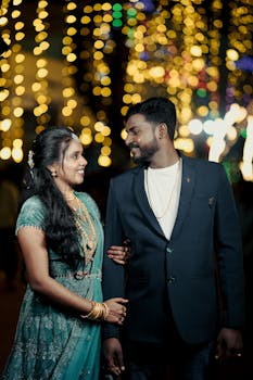 A happy couple at a vibrant South Asian wedding in Tamil Nadu with colorful bokeh lights.