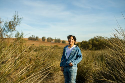 Free Portrait of a young adult in a denim jacket enjoying a sunny day in Morocco's countryside. Stock Photo