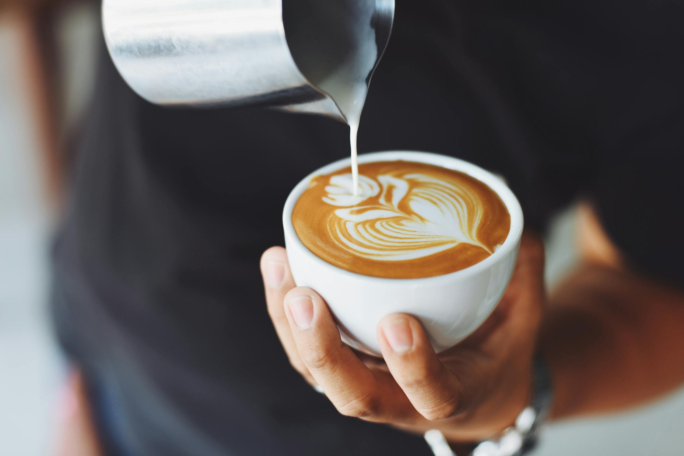 cream being poured over a glass of coffee