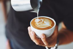 A flat white mid-pour at the counter