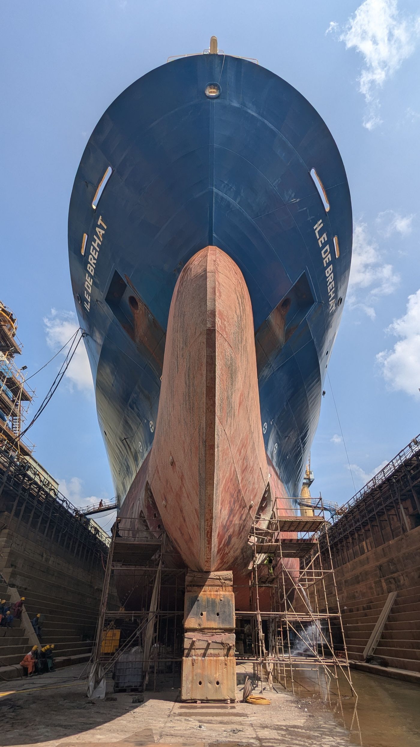 View looking up at a large ship hull supported in a dry dock