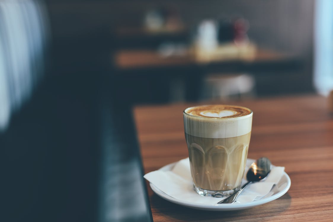 Free Clear Drinking Glass With Brown Beverage in White Saucer in Tilt Shift Photography Stock Photo