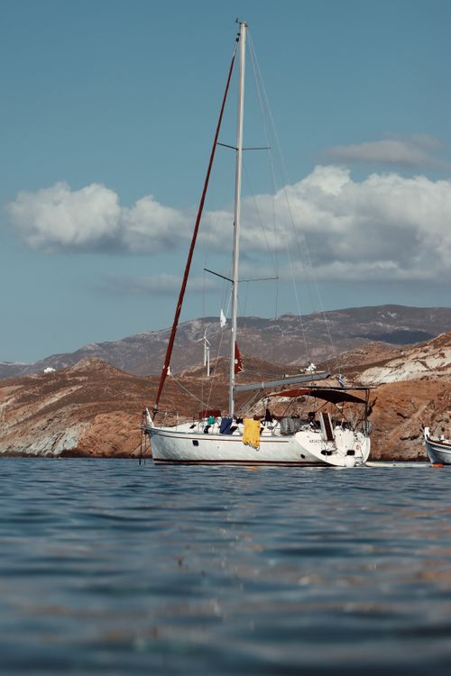 Free Serene view of a sailing yacht anchored off the rocky coast of Naxos in the Aegean Sea, Greece. Stock Photo