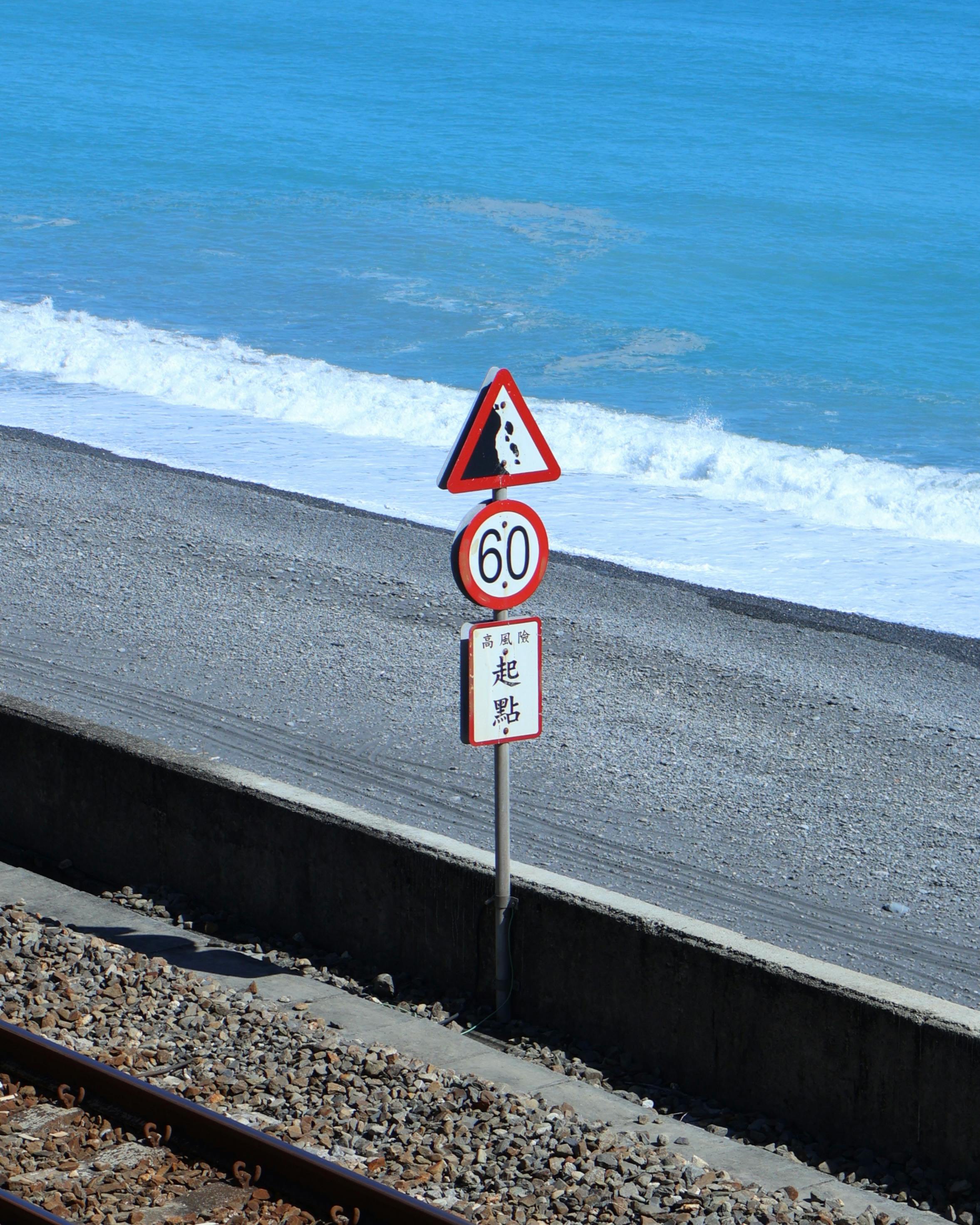 Oceanfront railway with erosion warning sign in Taitung County, Taiwan.