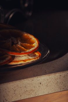 Artistic shot of dried orange slices on a plate with dark background, ideal for food-themed projects.