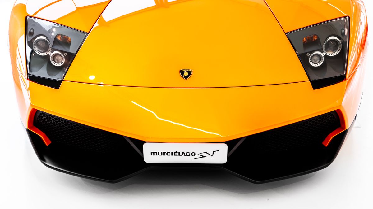 Prim-plan cu farurile si grila unui supercar portocaliu