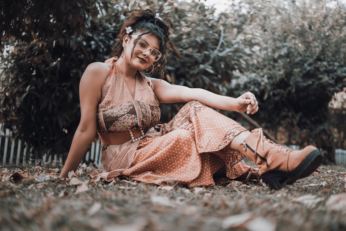 Stylish young woman in vintage boho outfit outdoors