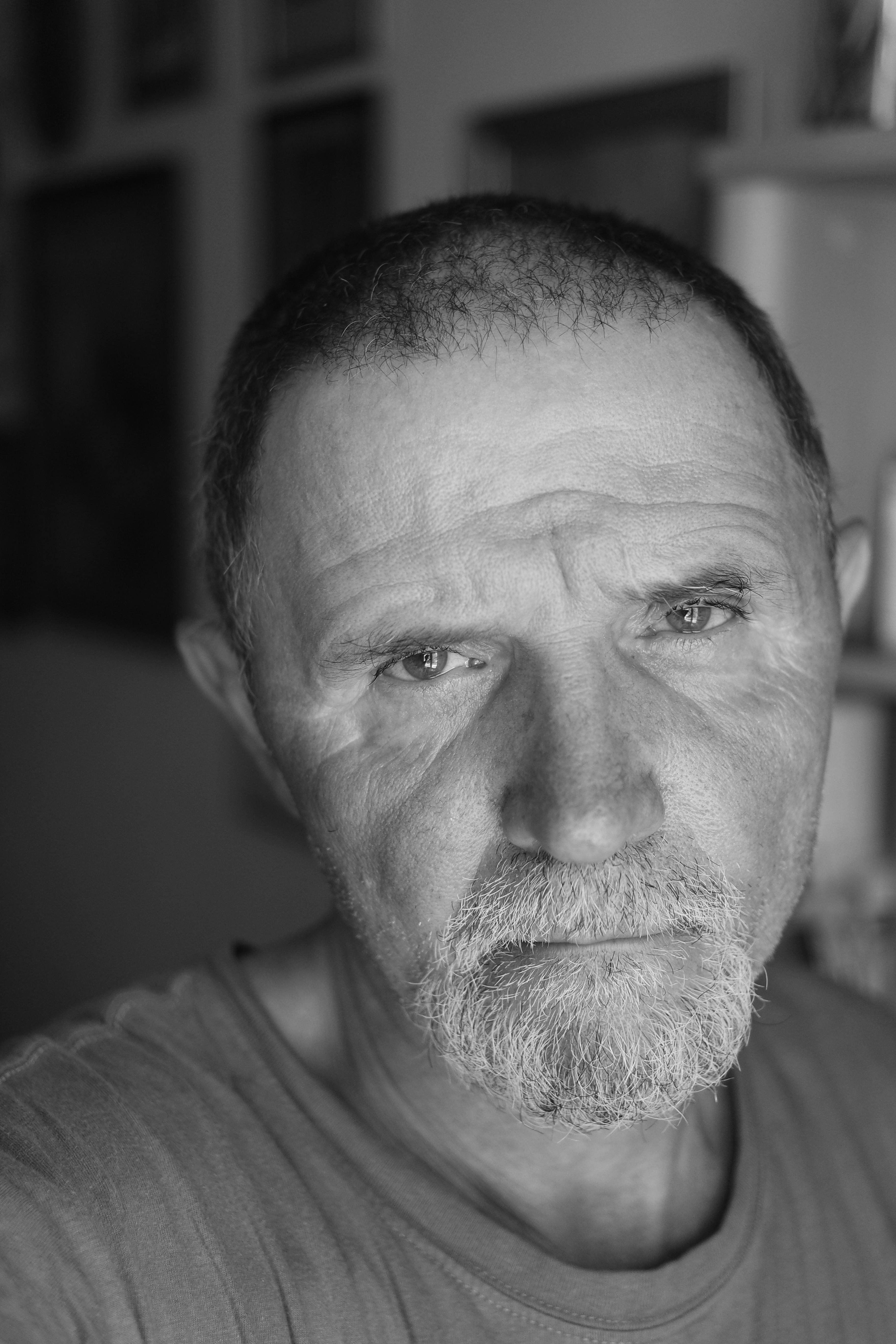 Close-up black and white portrait of a pensive senior man indoors, conveying deep thought and contemplation.