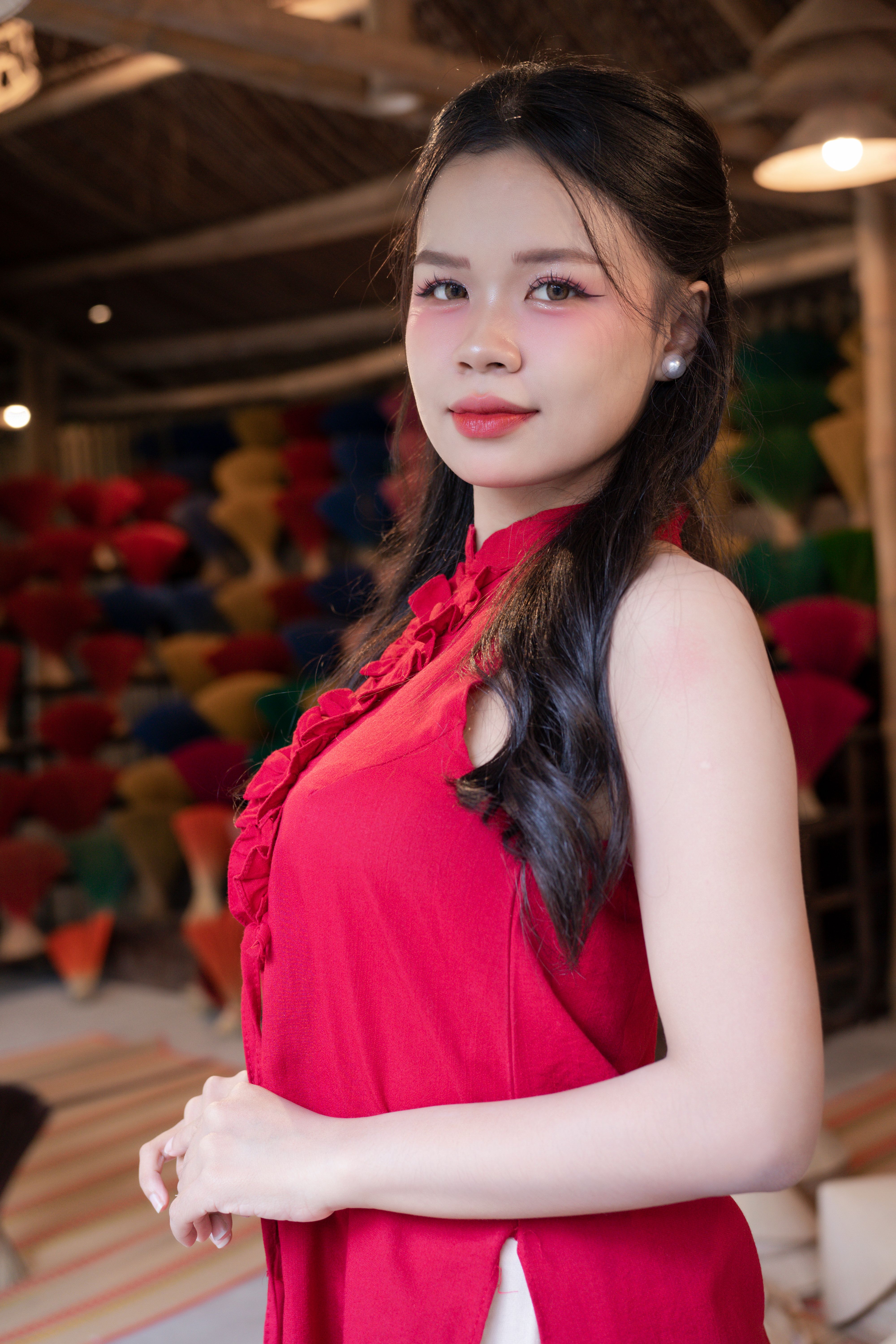 Elegant woman in a red dress posing indoors with a colorful and artistic background.