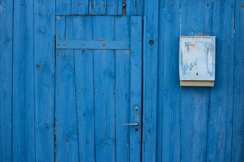 Free Close-up of a vibrant blue wooden door with a weathered mailbox, showcasing rustic charm. Stock Photo