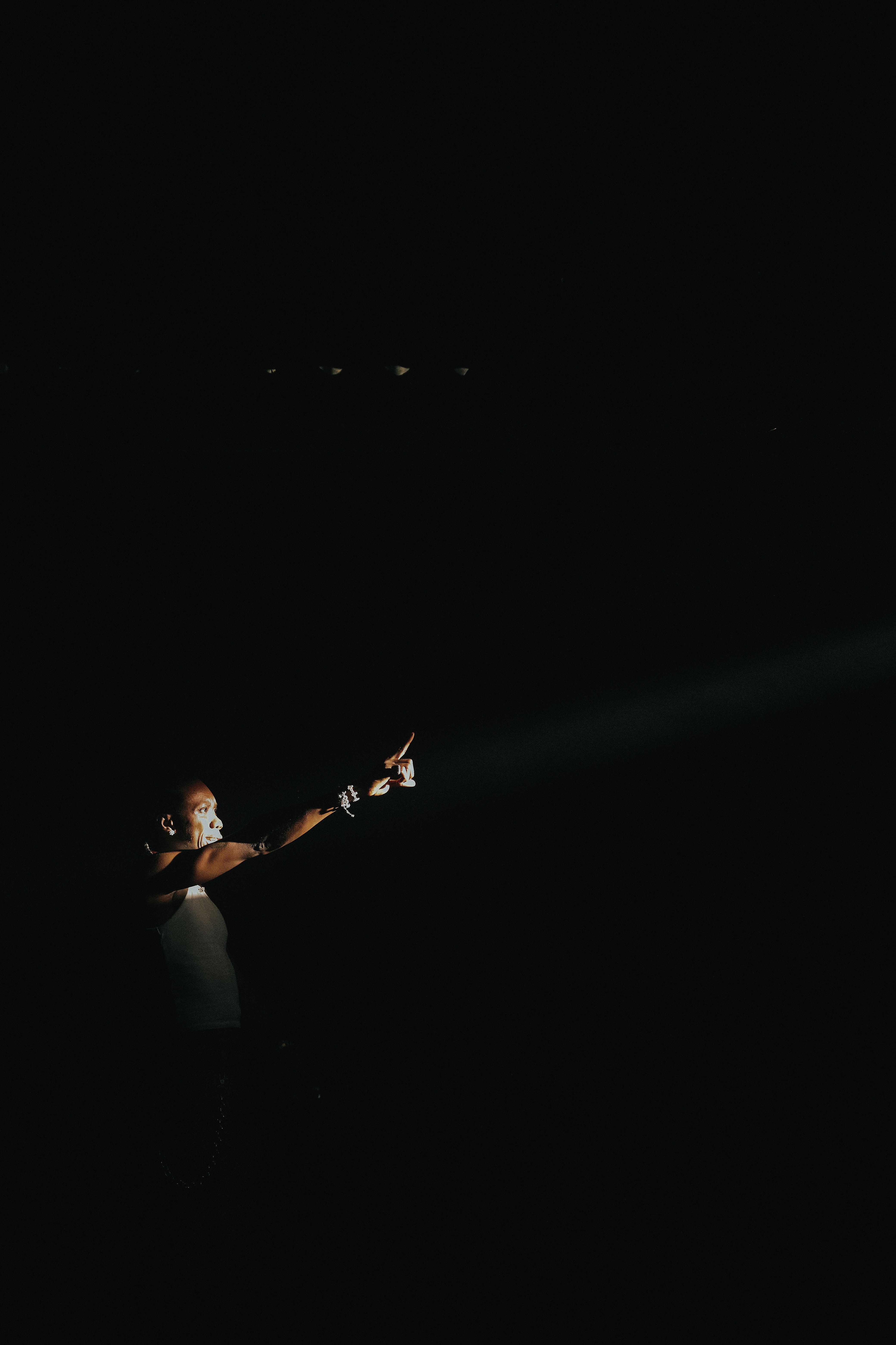 Gratis Immagine drammatica di un artista sul palco sotto una luce intensa in un ambiente buio. Foto a disposizione
